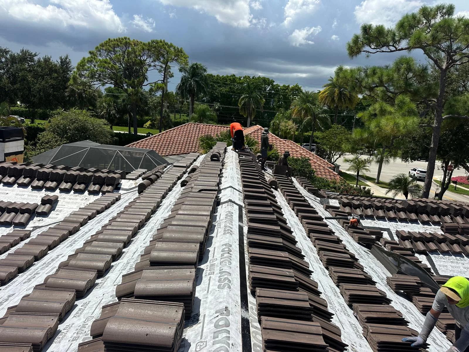Roofing crew distributing Barcelona 900 concrete roof tile across a Boca Raton roof