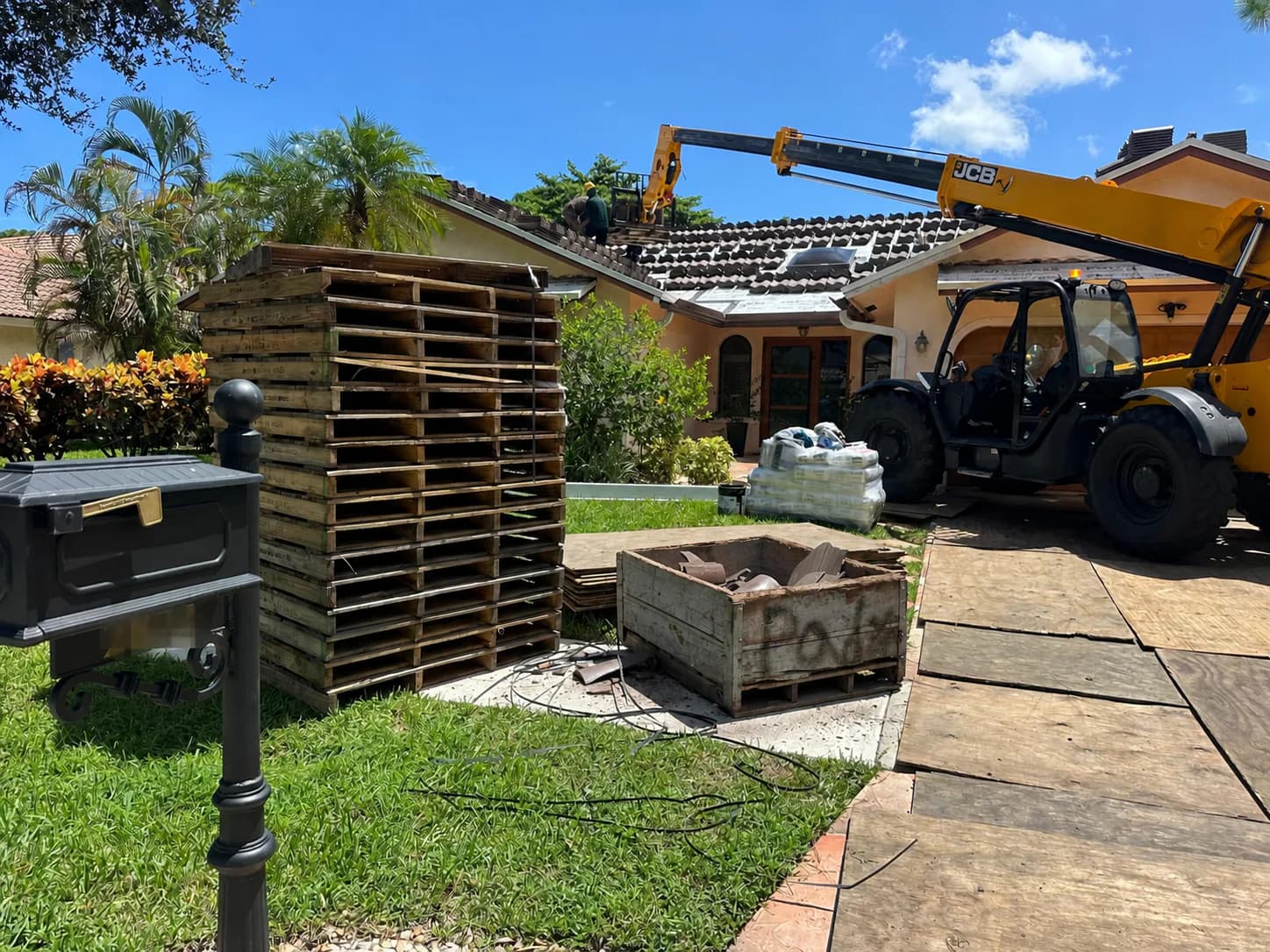 Telehandler positioned on a plywood-covered approach during Barcelona 900 rooftop tile loading in Boca Raton