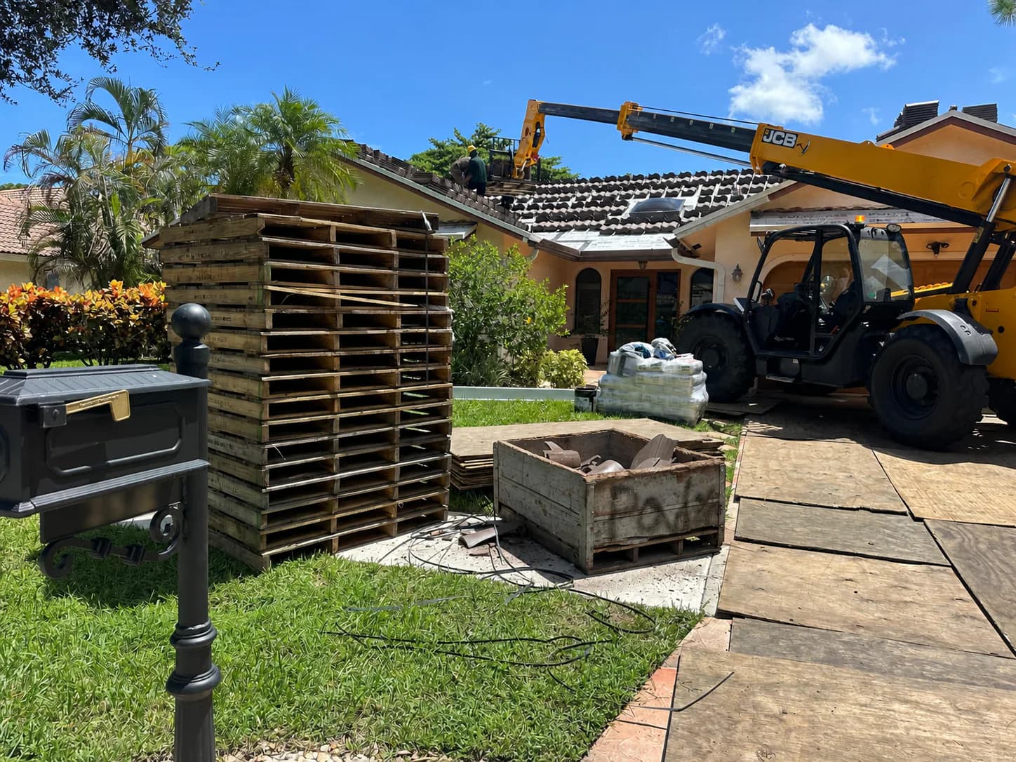 Second privacy-safe view of the telehandler and plywood-covered loading approach at a Boca Raton project