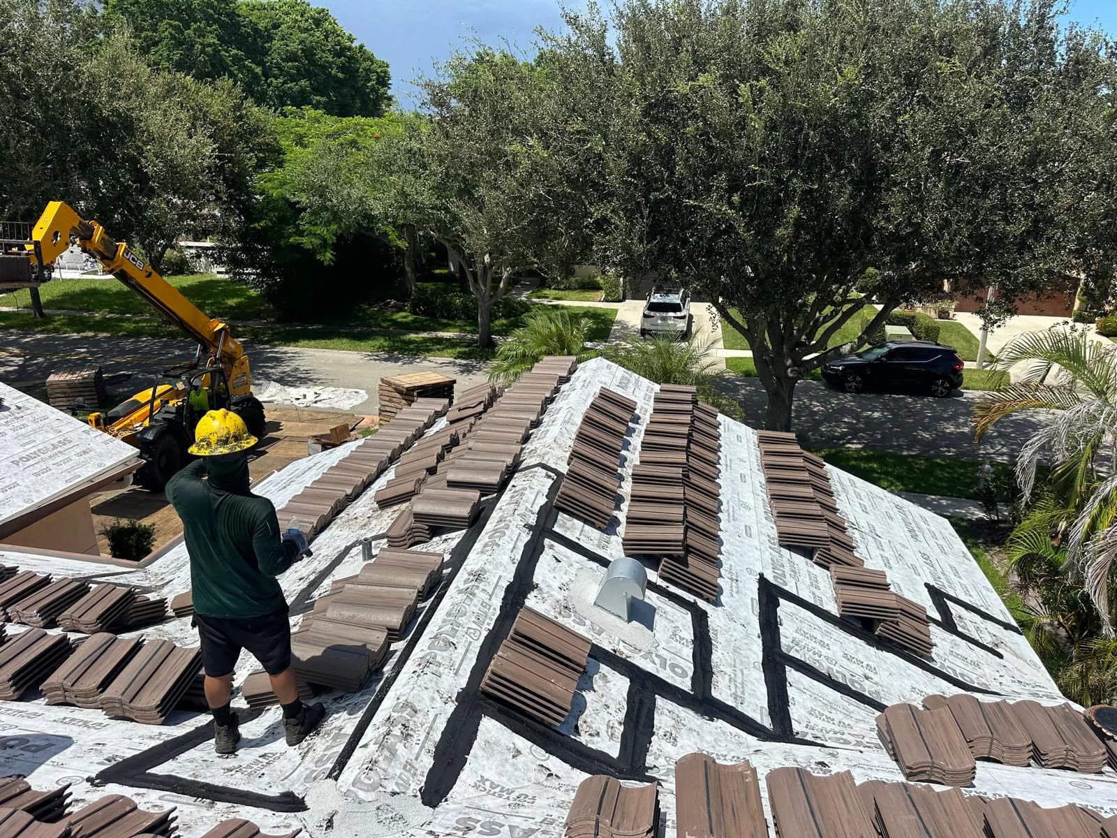 Telehandler and rooftop crew coordinating Barcelona 900 tile loading in Boca Raton