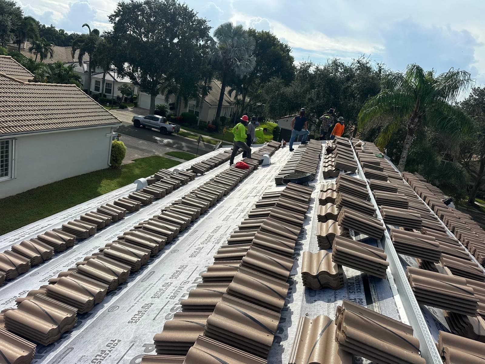 Rows of Estate roof tile organized across a prepared roof while the rooftop crew completes placement
