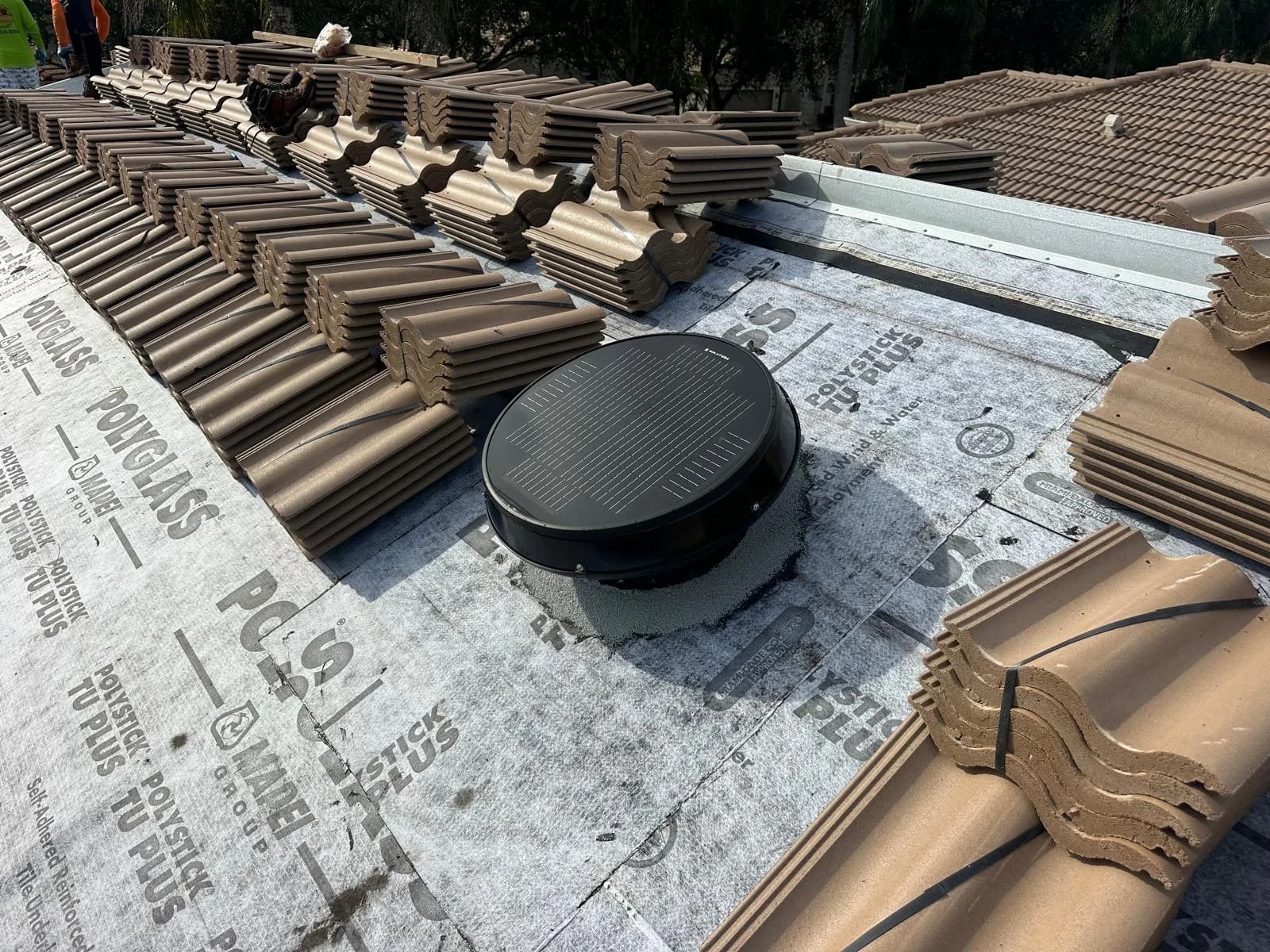 Estate field and trim tile staged around a roof vent during a Delray Beach rooftop-loading project