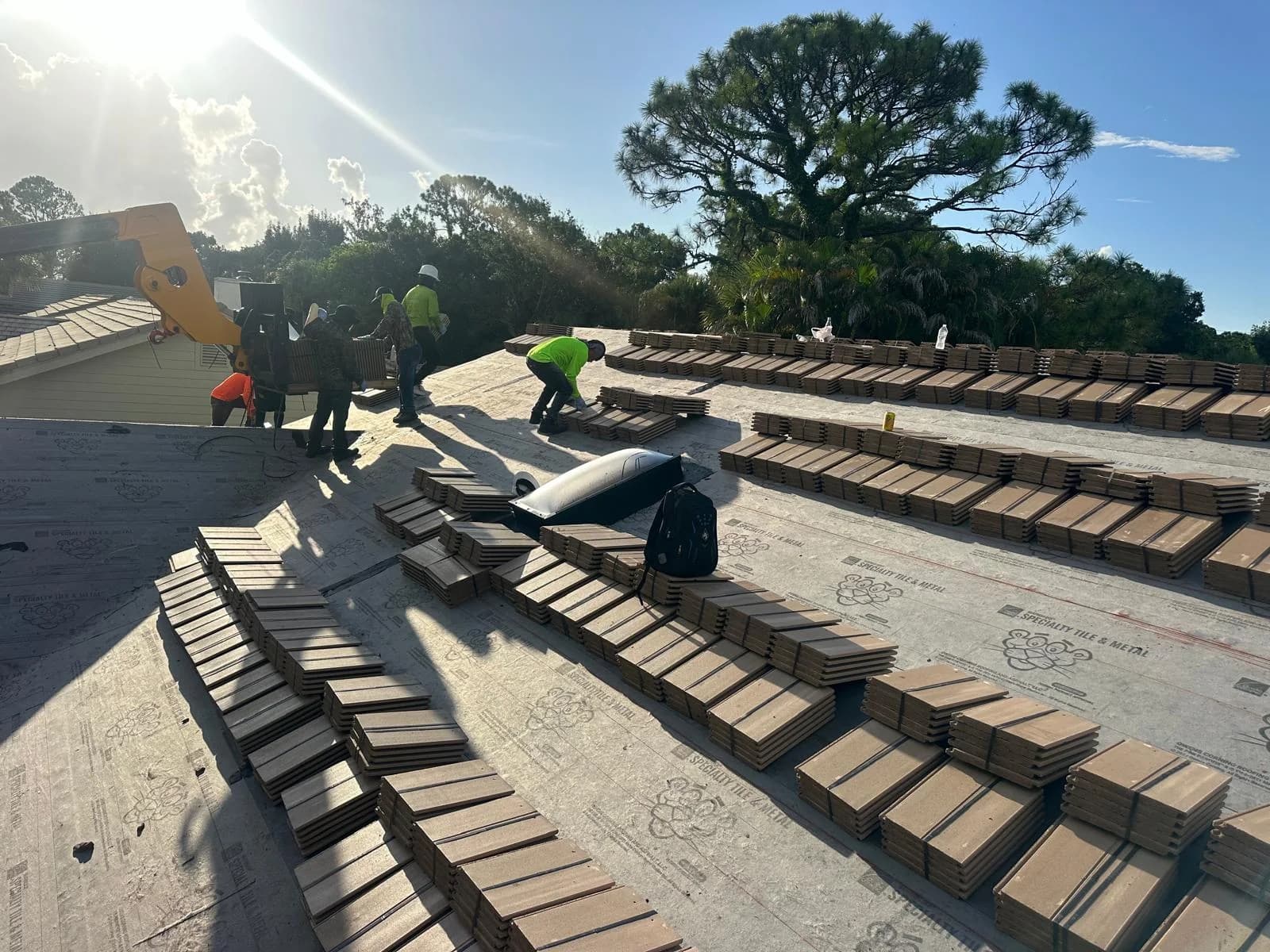 Telehandler and rooftop crew coordinating concrete tile loading in the Jupiter area