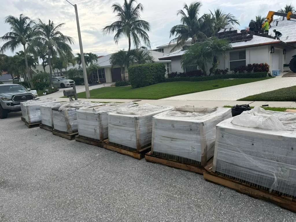 Wrapped Madera 900 roof tile pallets staged in North Palm Beach while a telehandler supplies the prepared roof