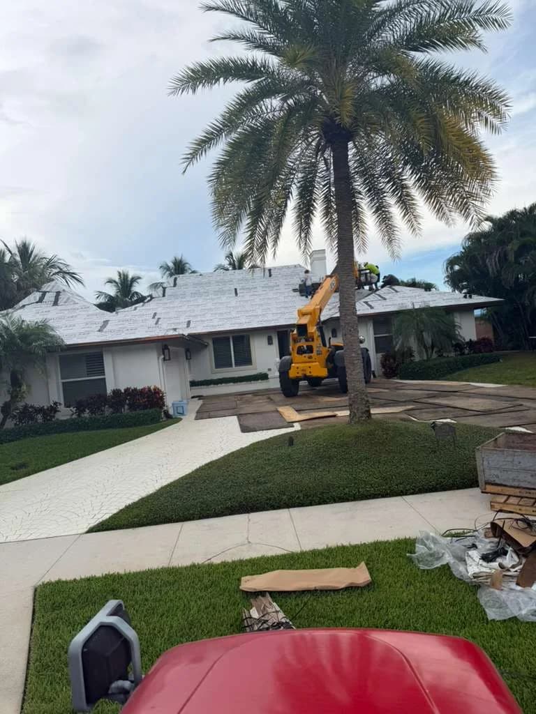 Telehandler positioned on a plywood-covered driveway during North Palm Beach roof tile loading