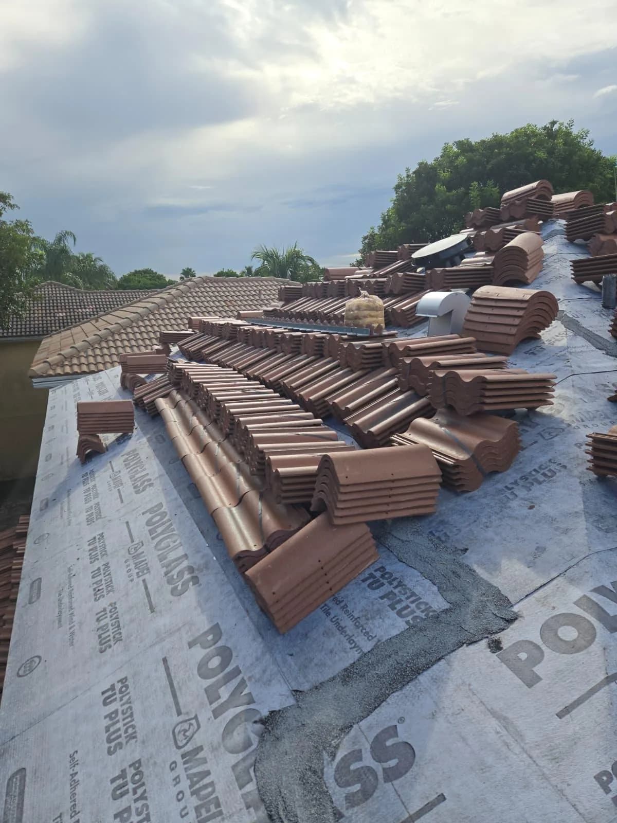 Villa 900 field and trim tile bundles distributed across the primary roof at a West Palm Beach-area project