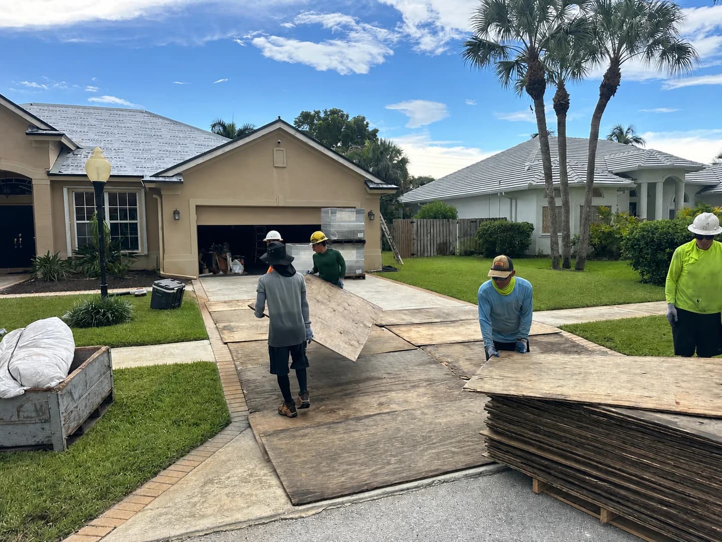 MMJ crew extending plywood driveway protection before rooftop tile loading in Jupiter