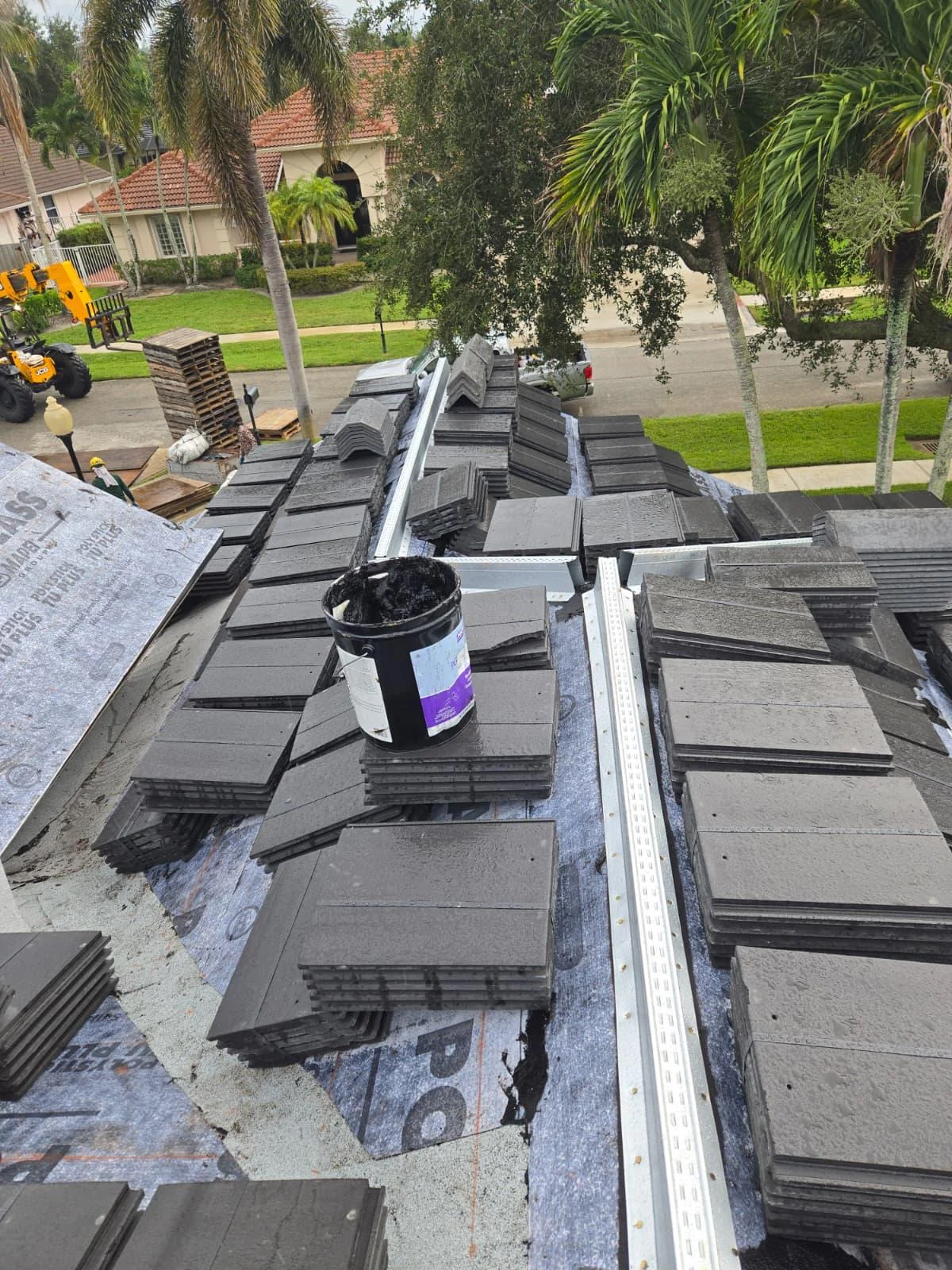 Telehandler and ground crew coordinating a Saxony 900 rooftop tile loading in Jupiter