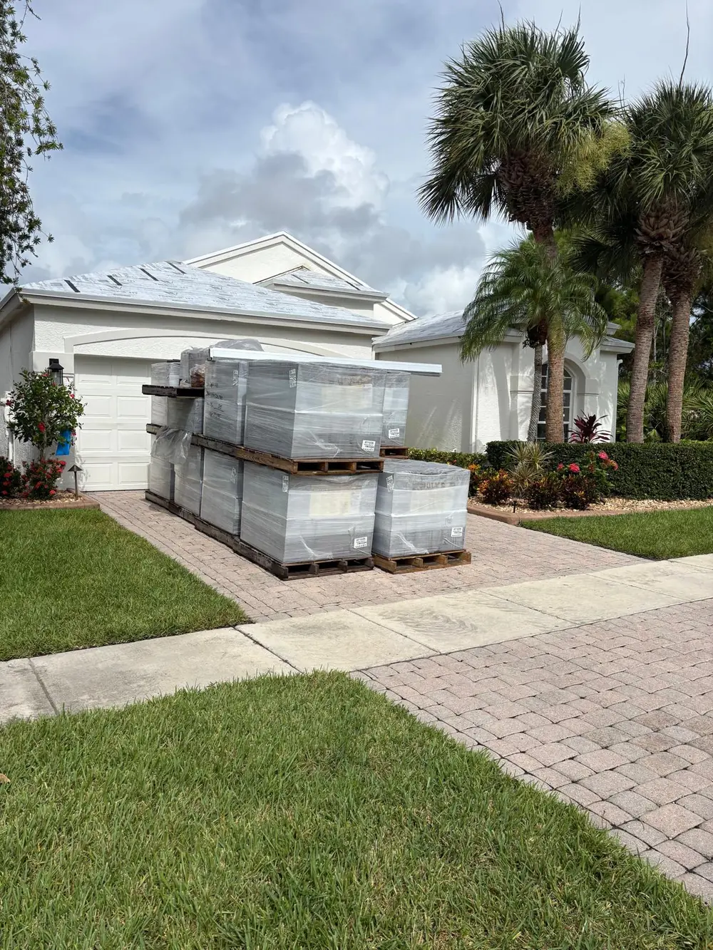 Wrapped roof tile pallets staged in a Florida residential driveway
